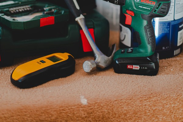 A hammer, drill, paint can and other tools on a carpeted stair
