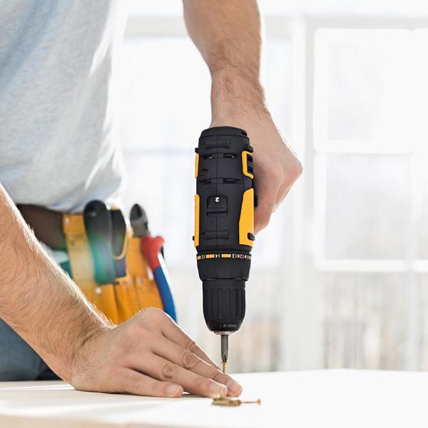A close-up of a man's hand drilling into a table