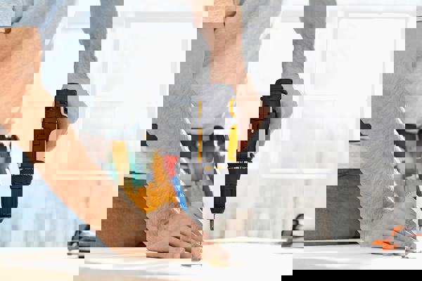 A close-up of a man's hand drilling into a table