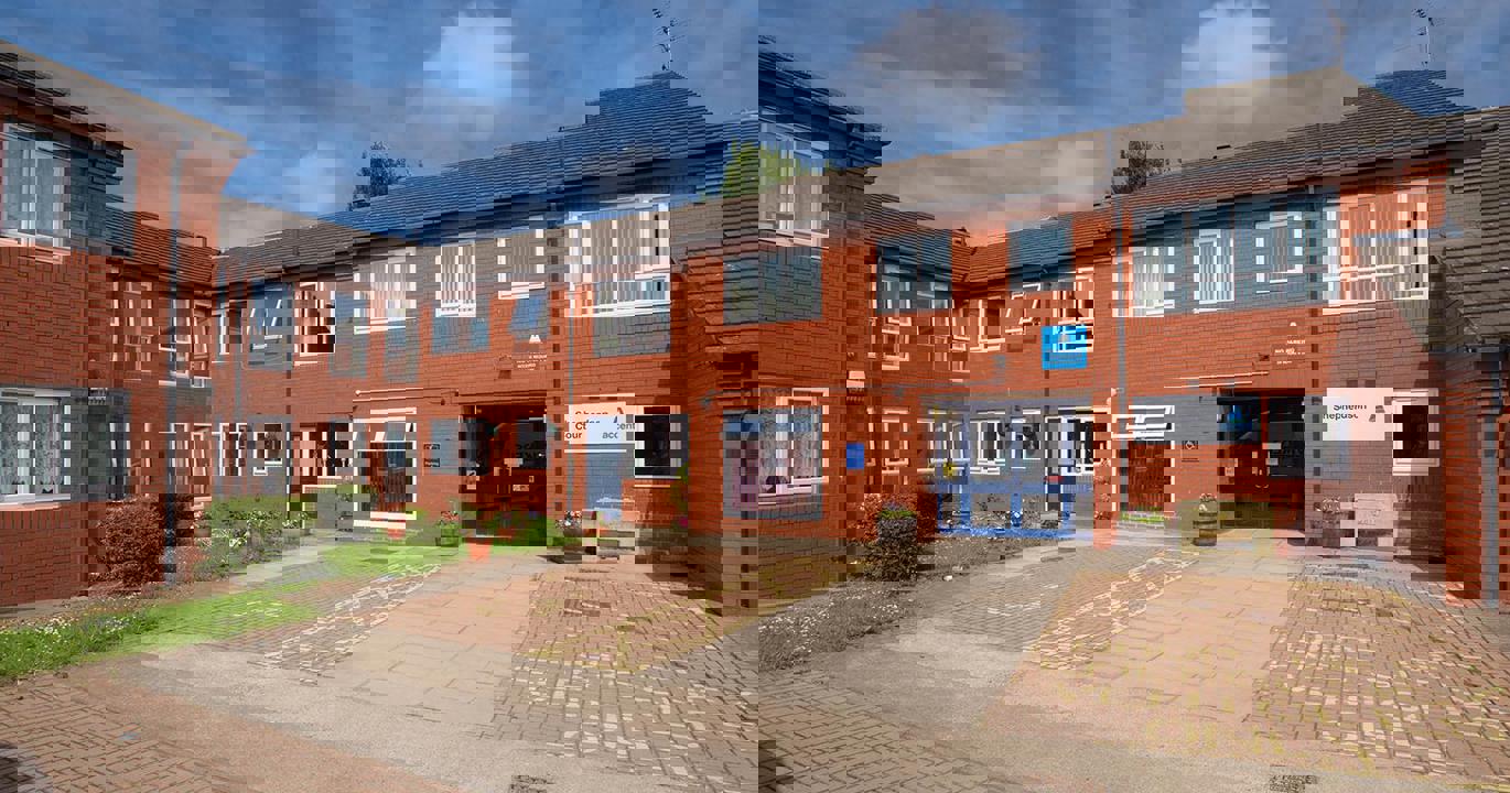 A red-brick two-storey housing development with wide driveways outside