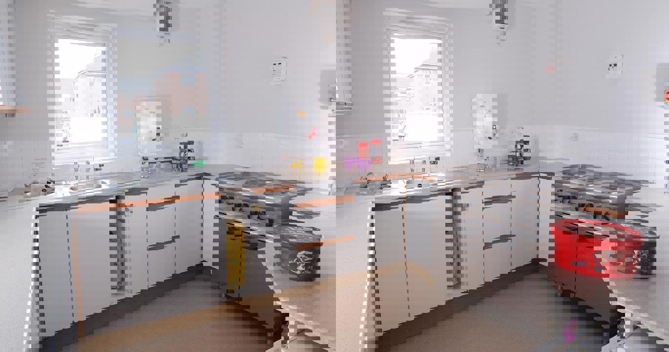 A communal kitchen with a sink, industrial-sized oven and a box of chocolates on the counter