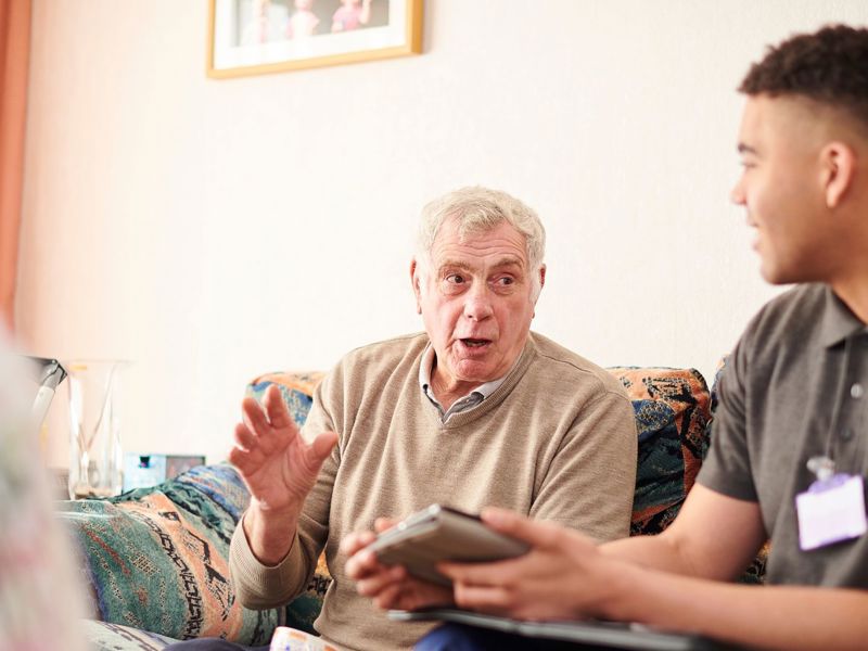 Man And Colleague Sat On Sofa Talking